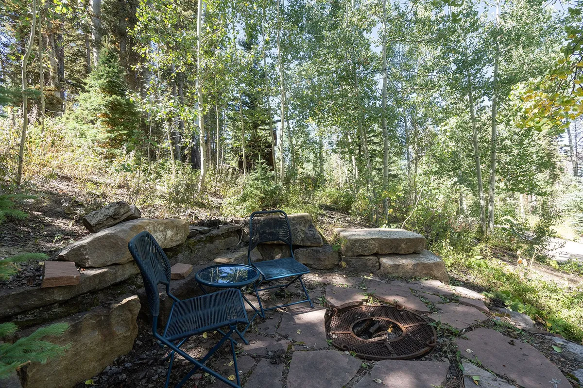 A cozy fire pit area with comfortable seating, encircled by trees. The scene is inviting for evening gatherings, relaxation, and enjoying the outdoors—all framed by the tranquility of the surrounding forest.